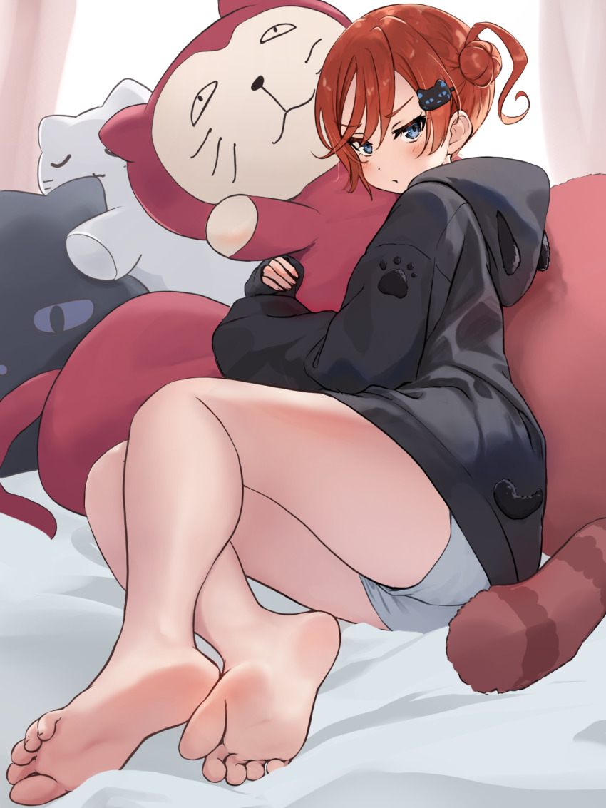 1girl, :t, bare_legs, barefoot, black_hoodie, blue_eyes, blush, cat_hair_ornament, closed_mouth, commentary_request, full_body, grey_shorts, hair_bun, hair_ornament, highres, hood, hood_down, hoodie, hugging_doll, hugging_object, long_sleeves, looking_at_viewer, love_live!, love_live!_superstar!!, lying, nekomaru_nisei, on_bed, on_side, partial_commentary, pout, red_hair, short_hair_with_long_locks, short_shorts, shorts, single_side_bun, sleeves_past_wrists, soles, solo, stuffed_animal, stuffed_cat, stuffed_toy, thighs, toes, v-shaped_eyebrows, yoneme_mei