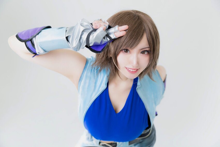 1girl, breasts, brown_hair, cleavage, cosplay, cosplay_photo, elbow_gloves, elle_piyo, female_focus, gloves, highres, jacket, kazama_asuka, kazama_asuka_(cosplay), large_breasts, looking_at_viewer, namco, photo_(medium), real_life, sleeveless, sleeveless_jacket, smile, solo, teeth, tekken
