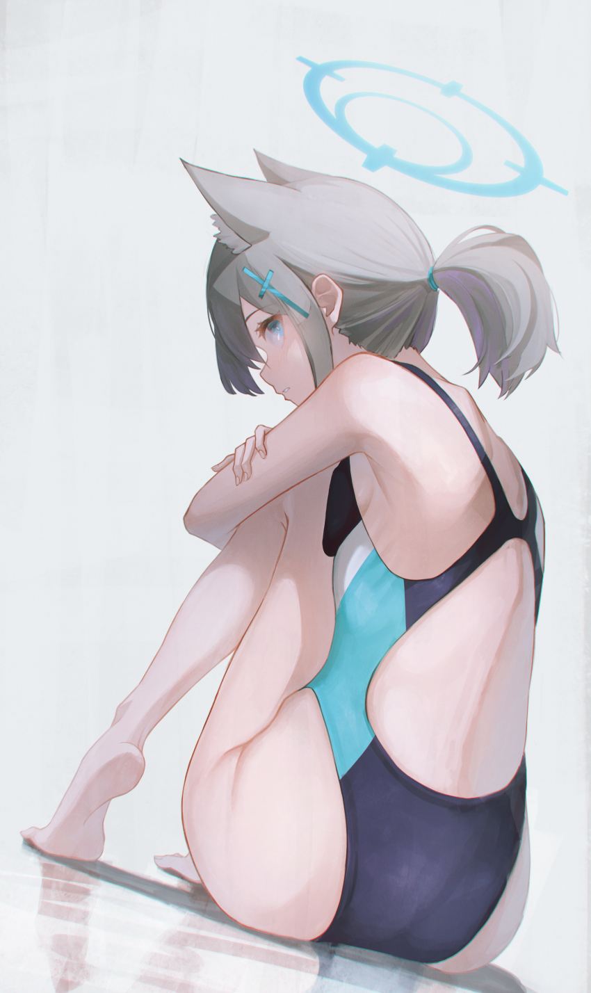 1girl, absurdres, alternate_hairstyle, animal_ear_fluff, animal_ears, back, back_focus, bare_legs, barefoot, black_one-piece_swimsuit, blue_archive, blue_eyes, blue_one-piece_swimsuit, commentary, competition_swimsuit, crossed_arms, dutch_angle, from_behind, grey_hair, halo, highleg, highleg_one-piece_swimsuit, highres, knees_to_chest, light_blush, looking_at_viewer, multicolored_swimsuit, official_alternate_costume, one-piece_swimsuit, ponytail, shiroko_(blue_archive), shiroko_(swimsuit)_(blue_archive), shoulder_blades, simple_background, solo, swimsuit, white_background, wolf_ears, yako_mashiro