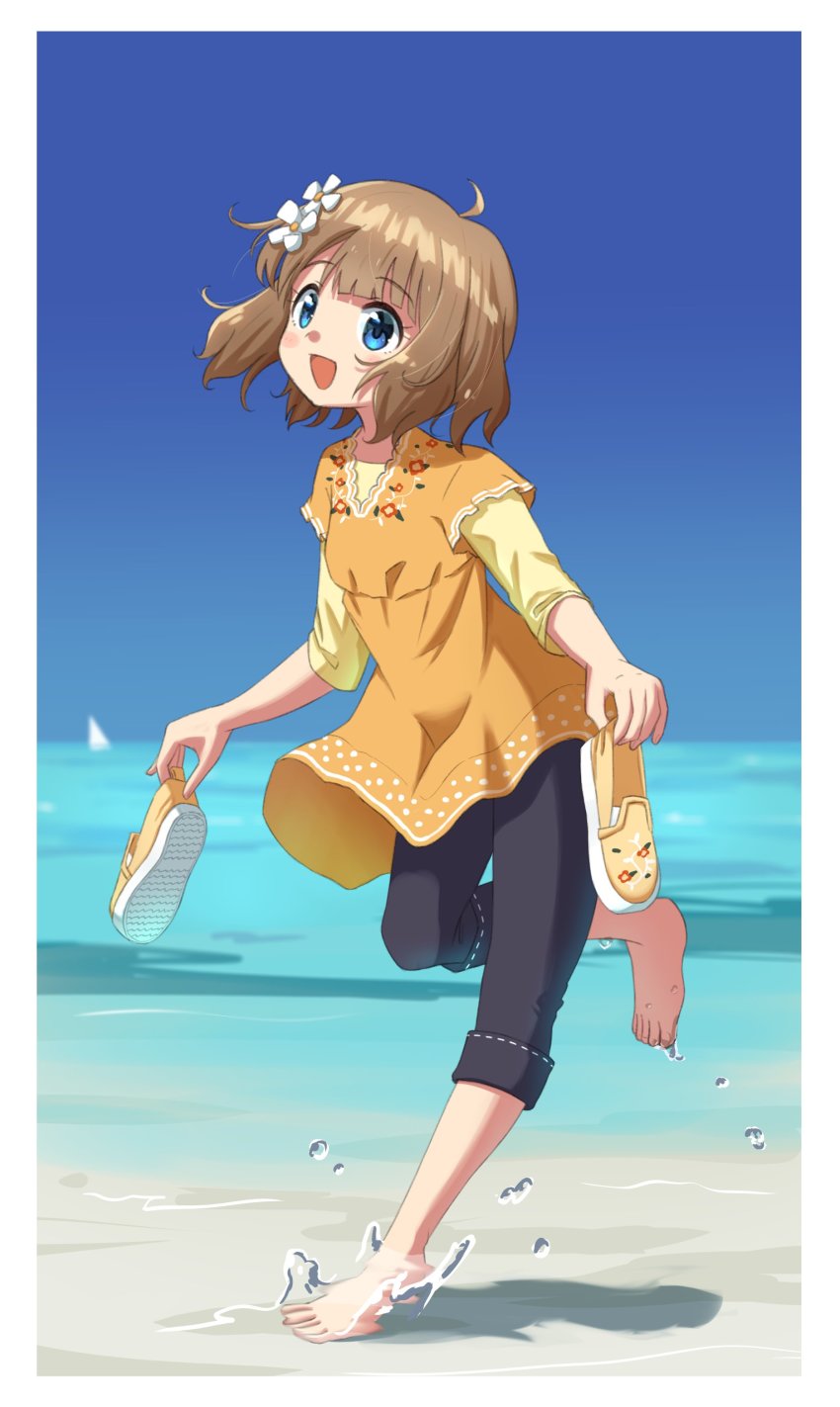 1girl, absurdres, ahoge, barefoot, beach, black_pants, blue_eyes, blue_sky, blush_stickers, brown_hair, child, commentary, day, dress, floral_print, flower, hair_flower, hair_ornament, highres, holding, holding_shoes, holding_unworn_clothes, houraijin, idolmaster, idolmaster_million_live!, long_sleeves, looking_at_viewer, ocean, open_mouth, pants, print_dress, shoes, short_hair, sidelocks, sky, smile, solo, standing, standing_on_one_leg, suou_momoko, unworn_shoes, water_drop, wavy_hair, yellow_dress, yellow_shoes