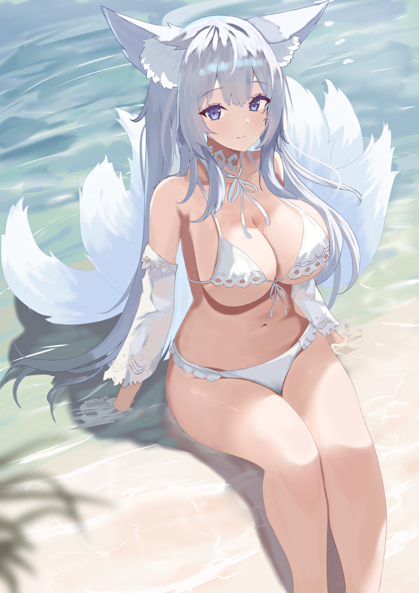 1girl, animal_ear_fluff, animal_ears, arm_rest, azur_lane, beach, bikini, blue_eyes, breasts, cleavage, closed_mouth, detached_sleeves, fox_ears, fox_tail, highres, kitsune, large_breasts, long_hair, looking_at_viewer, mole, mole_under_eye, natsuki_(natsu_1936), navel, official_alternate_costume, outdoors, sand, see-through_clothes, see-through_sleeves, shinano_(azur_lane), shinano_(dreamy_white_sands)_(azur_lane), sitting, smile, solo, stomach, swimsuit, tail, water, white_bikini, white_hair, white_tail