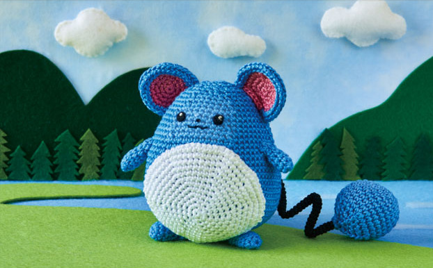 amigurumi_(medium), asako_ito, black_eyes, blue_sky, closed_mouth, clouds, cloudy_sky, commentary, creature, day, english_commentary, full_body, gen_2_pokemon, grass, marill, multiple_sources, nature, no_humans, official_art, outdoors, photo, pokemon, pokemon_(creature), pokemon_trading_card_game, sky, solo, standing, third-party_source, tree