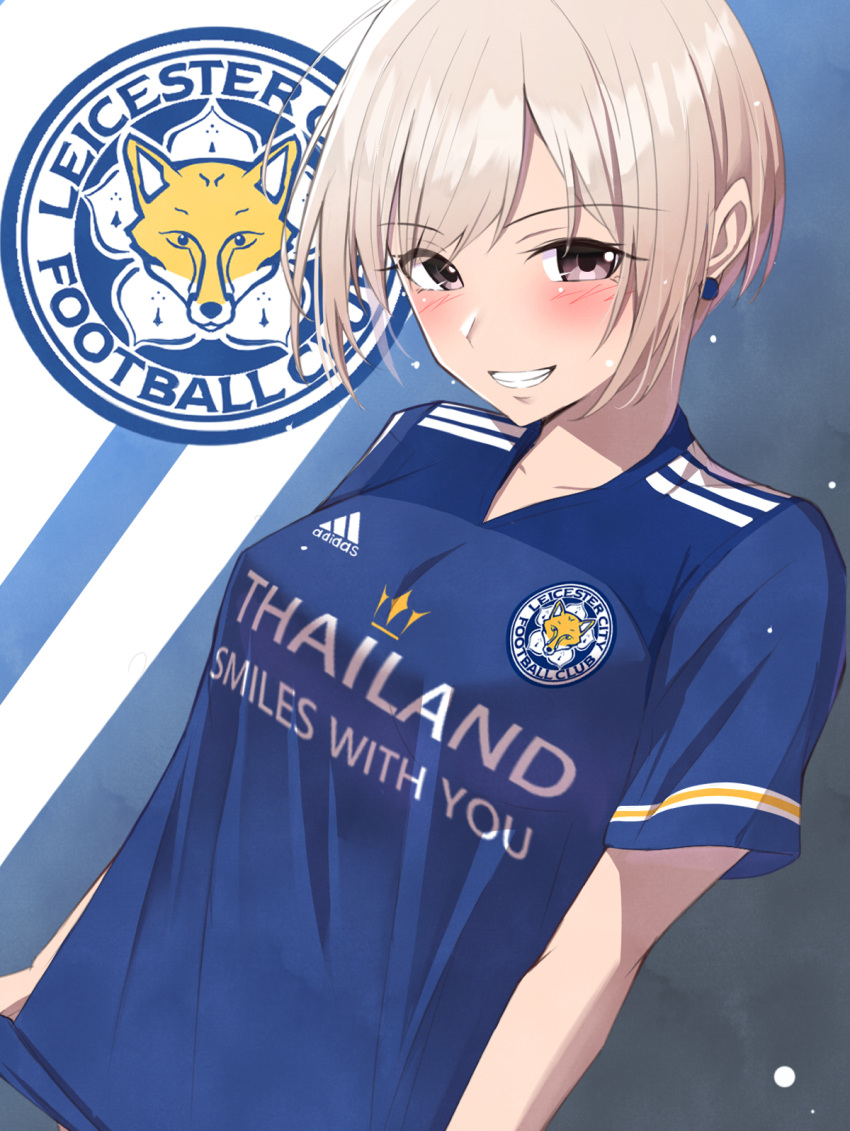 1girl, adidas, bangs, blonde_hair, blue_background, blue_shirt, blush, breasts, brown_eyes, clothes_writing, collarbone, commentary_request, earrings, eyebrows_visible_through_hair, grin, highres, idolmaster, idolmaster_cinderella_girls, jewelry, k-chitsu, leicester_city_fc, logo, looking_at_viewer, medium_breasts, parted_bangs, premier_league, shiomi_shuuko, shirt, short_hair, short_sleeves, sidelocks, smile, soccer_uniform, solo, sportswear, standing, teeth, trait_connection, two-tone_background, upper_body, white_background