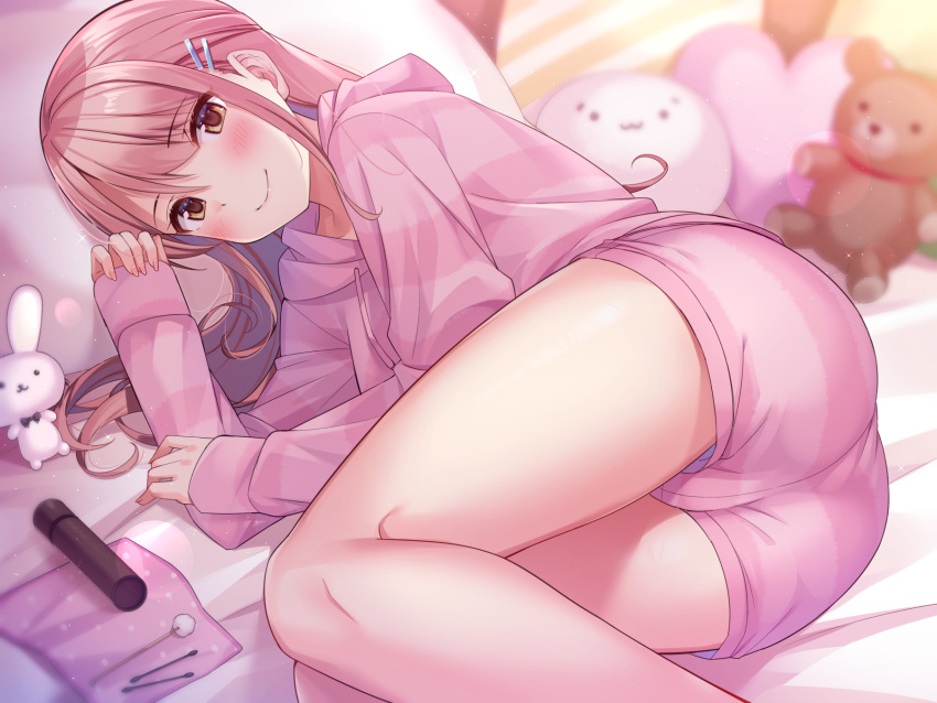 1girl, ass, bed, blush, brown_eyes, brown_hair, hair_ornament, hairclip, highres, hood, hoodie, long_hair, looking_at_viewer, lying, on_bed, on_pillow, on_side, original, pajamas, pillow, pink_hoodie, pink_pajamas, pink_shorts, rabbit, shorts, smile, stuffed_animal, stuffed_toy, super_nagoyaka, teddy_bear