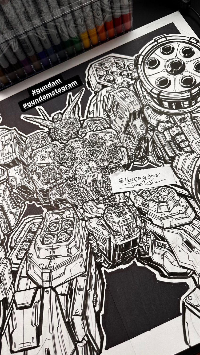 art_tools_in_frame, english_commentary, gift_art, greyscale, gundam, gundam_heavyarms, gundam_wing, highres, ink_(medium), james_raiz, mecha, mecha_focus, mobile_suit, monochrome, no_humans, photo_(medium), robot, science_fiction, signature, traditional_media, twitter_username, v-shaped_eyebrows