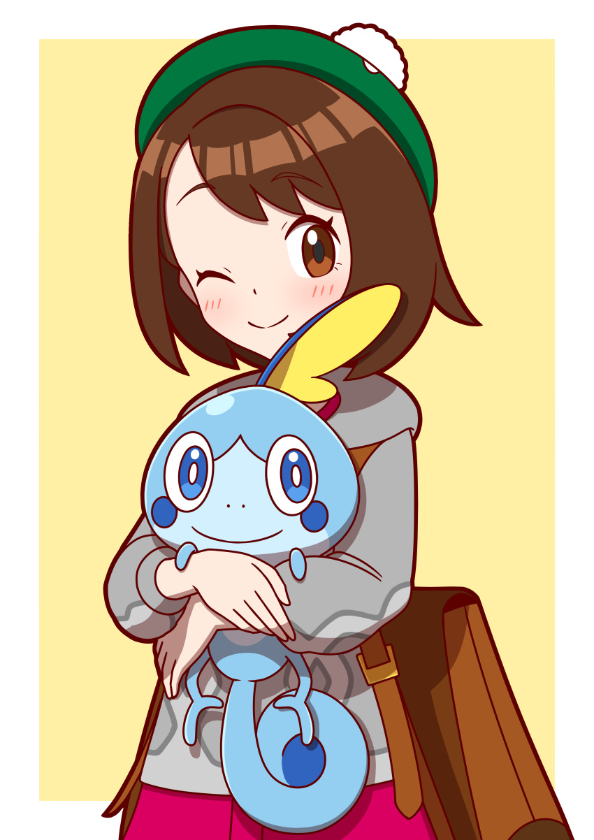 1girl, ;), absurdres, backpack, bag, blush, border, brown_bag, brown_eyes, brown_hair, cardigan, closed_mouth, commentary_request, dress, eyelashes, gloria_(pokemon), green_hat, grey_cardigan, happy, hat, highres, holding, holding_pokemon, hood, hood_down, hooded_cardigan, one_eye_closed, outside_border, pink_dress, pokemon, pokemon_(creature), pokemon_swsh, smile, sobble, tam_o'_shanter, white_border, yellow_background, zitome_i
