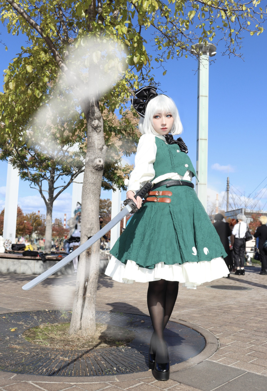1girl, absurdres, black_bow, black_bowtie, black_footwear, black_hairband, black_pantyhose, blue_sky, bow, bowtie, cosplay_photo, day, full_body, green_skirt, green_vest, hairband, highres, holding, holding_sword, holding_weapon, katana, konpaku_youmu, konpaku_youmu_(ghost), long_sleeves, outdoors, pantyhose, pavement, perle_oekaki, photo_(medium), shirt, skirt, skirt_set, sky, solo_focus, standing, sword, touhou, tree, vest, weapon, white_hair, white_shirt