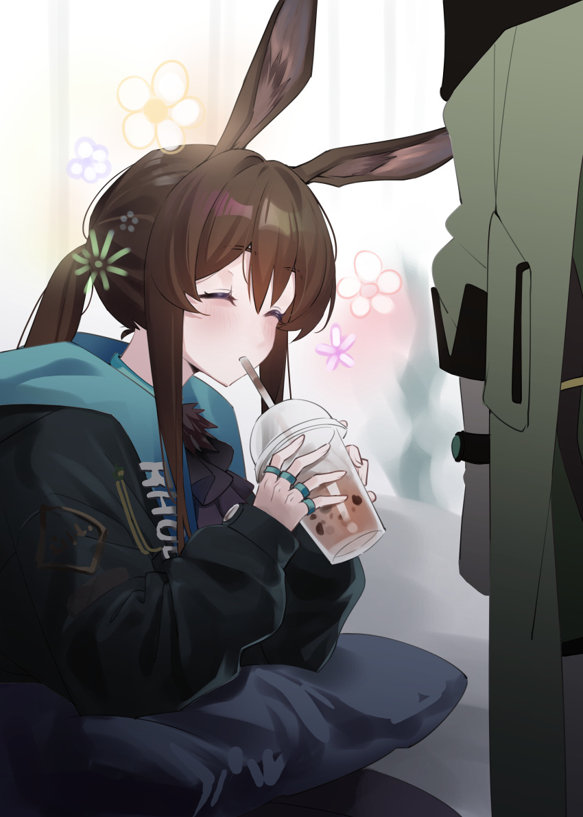 1girl, 97_mubi_bai, absurdres, amiya_(arknights), animal_ears, arknights, ascot, black_ascot, black_jacket, brown_hair, bubble_tea, closed_eyes, commentary_request, cup, disposable_cup, donkey_ears, donkey_girl, drinking, drinking_straw, drinking_straw_in_mouth, flower, highres, holding, holding_cup, hood, hood_down, hooded_jacket, jacket, jewelry, long_hair, long_sleeves, multiple_rings, pillow, ponytail, ring, sidelocks, solo, sparkle