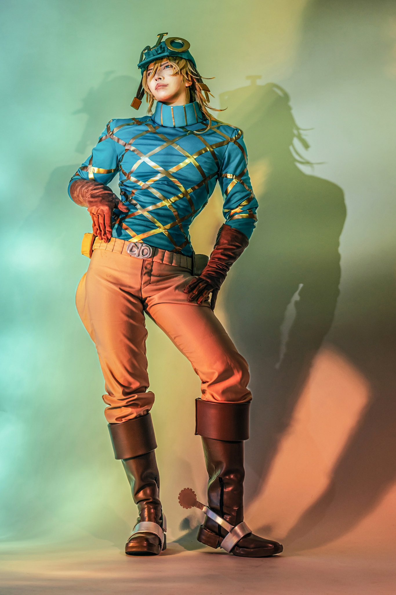 1boy, 24oo3oo42, argyle_clothes, argyle_sweater, belt, belt_buckle, bishounen, blonde_hair, blue_sweater, boots, brown_belt, brown_boots, brown_gloves, brown_pants, buckle, closed_mouth, commentary_request, contrapposto, cosplay, cosplay_photo, cowboy_boots, diego_brando, diego_brando_(cosplay), full_body, gloves, hand_on_own_hip, highres, jodhpurs, jojo_no_kimyou_na_bouken, knee_boots, long_sleeves, looking_at_viewer, male_focus, medium_hair, pants, photo_(medium), shadow, solo, spurs, standing, steel_ball_run, sweater, turtleneck, turtleneck_sweater