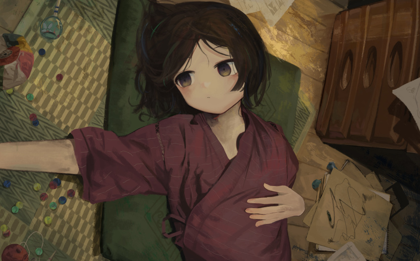 1girl, absurdres, black_hair, brown_eyes, cushion, drawing_(object), eliot_(eokaitekaite969), floor, hand_on_own_stomach, highres, japanese_clothes, lying, marble_(toy), on_back, on_cushion, original, paper, pencil, pencil_sharpener, short_sleeves, tansu_(cabinet), upper_body, wooden_floor
